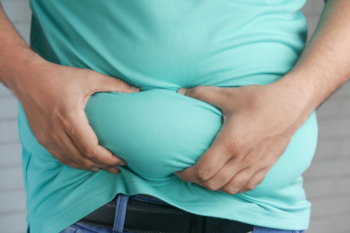 A person holding excess body fat around the waist.
