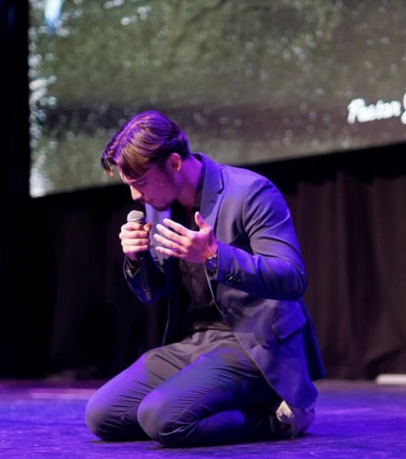 Robin Kramps kneeling in prayer on stage.